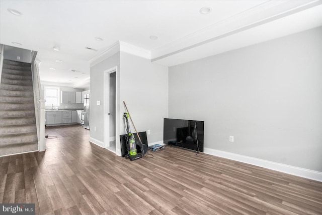 unfurnished living room featuring ornamental molding and wood-type flooring