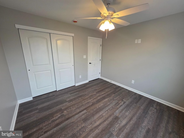 unfurnished bedroom featuring dark wood-type flooring, a ceiling fan, baseboards, and a closet