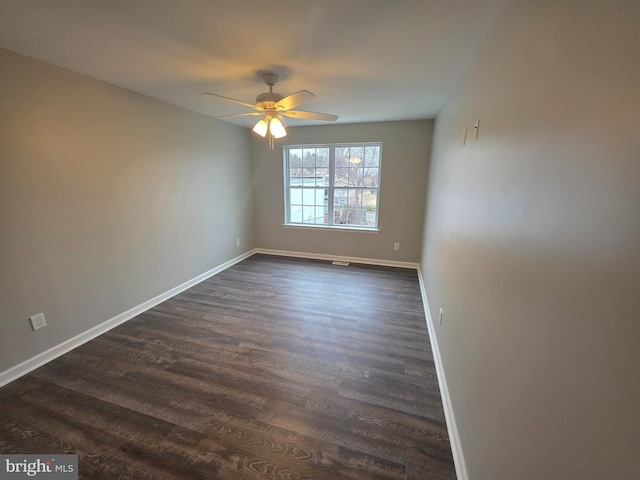 empty room with dark wood finished floors, baseboards, and ceiling fan