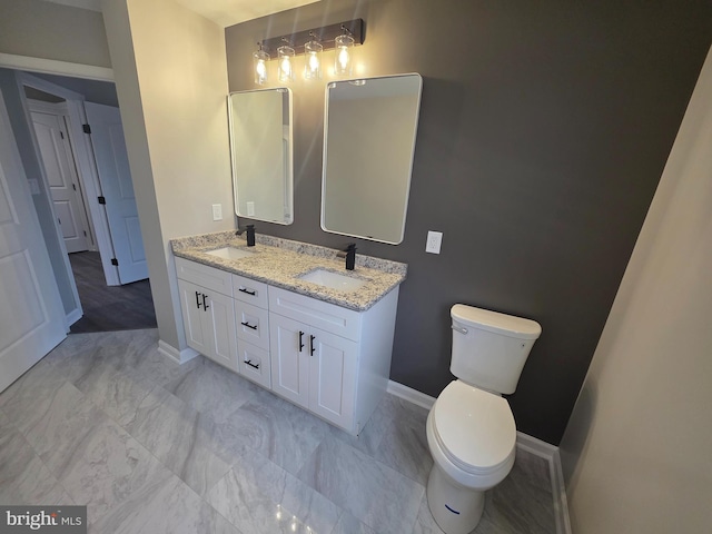 full bath featuring baseboards, a sink, toilet, and double vanity