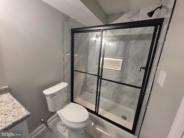 bathroom featuring toilet, a stall shower, baseboards, and vanity