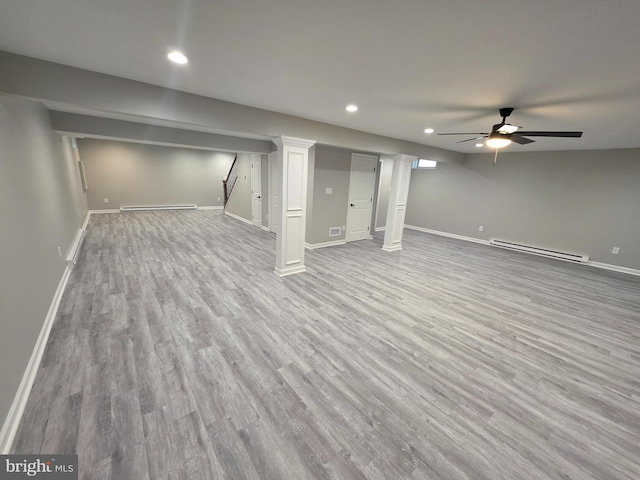 finished basement featuring a baseboard radiator, wood finished floors, baseboards, and a baseboard heating unit