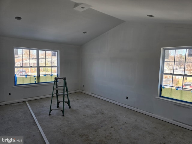 unfurnished room with lofted ceiling and concrete floors