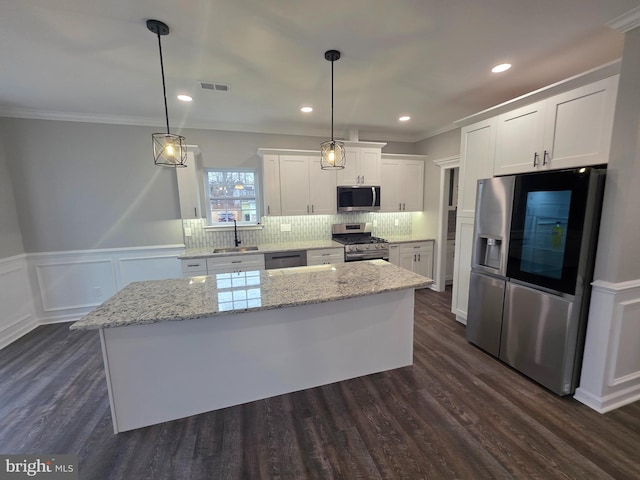 kitchen with visible vents, a center island, white cabinetry, appliances with stainless steel finishes, and decorative backsplash