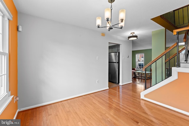 interior space featuring stairway, an inviting chandelier, wood finished floors, and baseboards