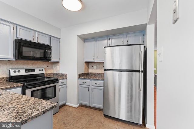 kitchen featuring light tile patterned floors, stainless steel appliances, gray cabinets, backsplash, and dark stone countertops