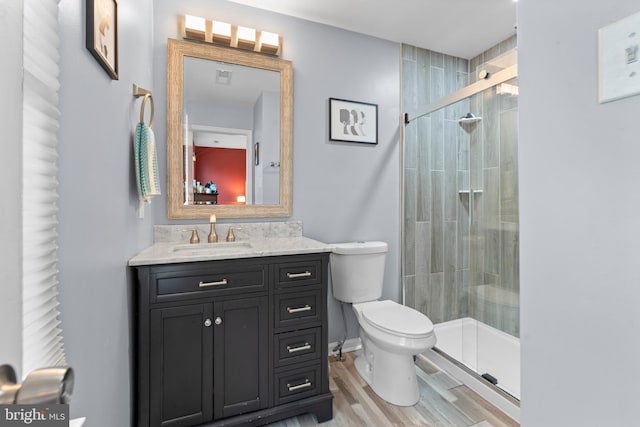 full bathroom with toilet, a shower stall, wood finished floors, and vanity