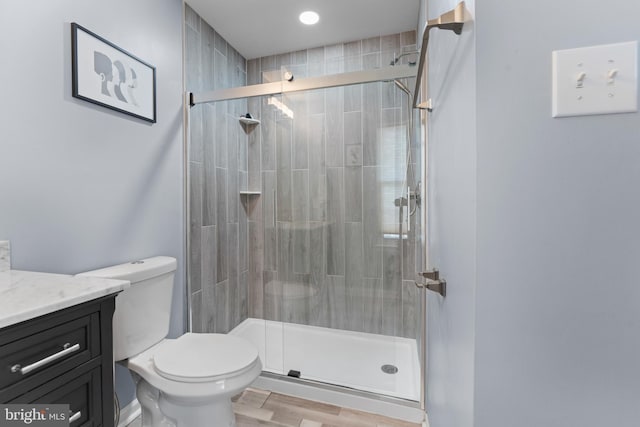 full bath featuring a stall shower, vanity, toilet, and wood finished floors