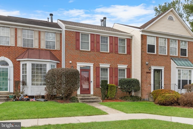 multi unit property featuring brick siding and a front lawn