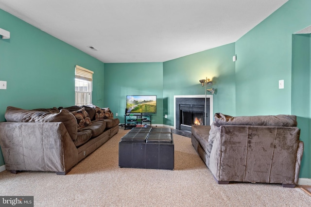 living area featuring a warm lit fireplace, carpet floors, visible vents, and baseboards