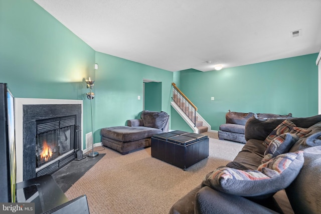 carpeted living room featuring a fireplace with flush hearth, stairs, baseboards, and visible vents