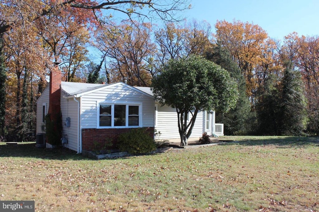 view of side of home featuring central air condition unit and a yard