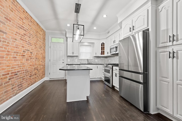 kitchen featuring decorative light fixtures, a kitchen island, white cabinetry, stainless steel appliances, and brick wall