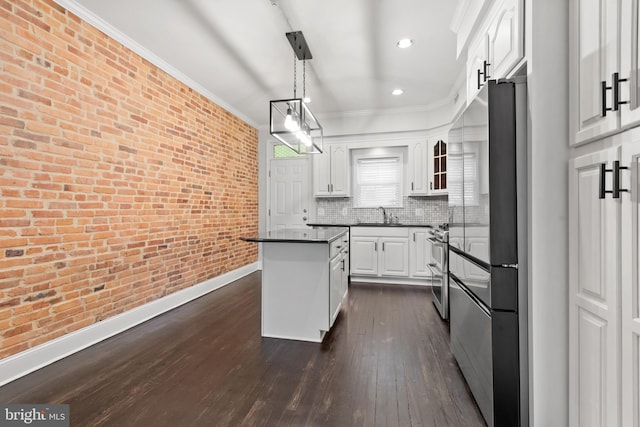 kitchen featuring pendant lighting, white cabinets, decorative backsplash, appliances with stainless steel finishes, and brick wall