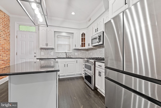 kitchen with backsplash, sink, appliances with stainless steel finishes, a kitchen island, and white cabinetry