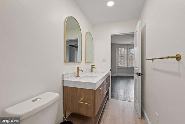 bathroom with wood-type flooring, vanity, toilet, and ceiling fan