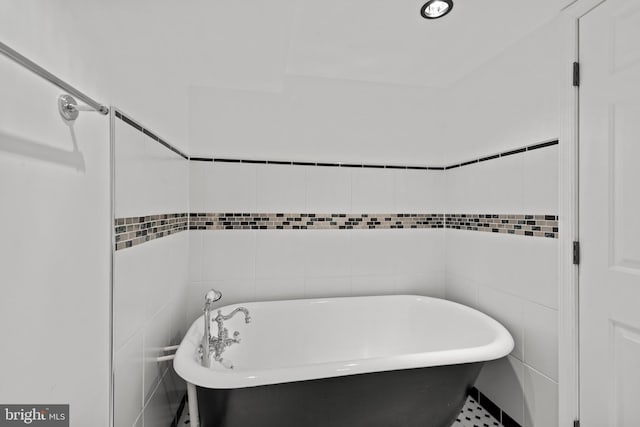 bathroom with a bathing tub and tile walls