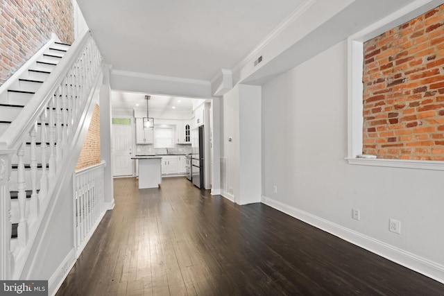 unfurnished living room featuring a chandelier, dark hardwood / wood-style flooring, ornamental molding, and sink