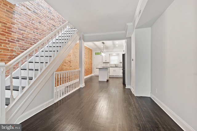 interior space with dark hardwood / wood-style floors, sink, crown molding, and brick wall