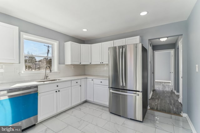 kitchen with appliances with stainless steel finishes, sink, white cabinets, and backsplash