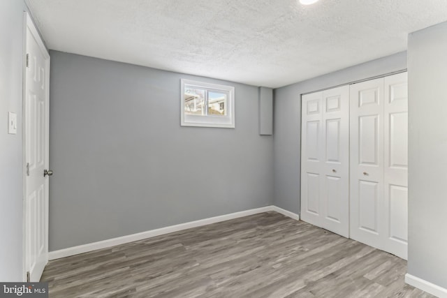 unfurnished bedroom with hardwood / wood-style flooring, a closet, and a textured ceiling