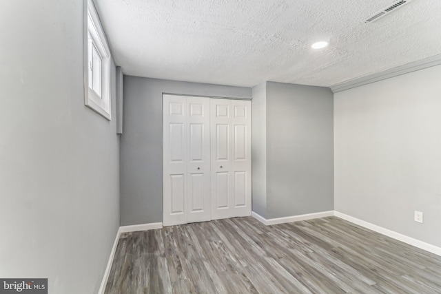 unfurnished bedroom featuring hardwood / wood-style floors, a closet, and a textured ceiling