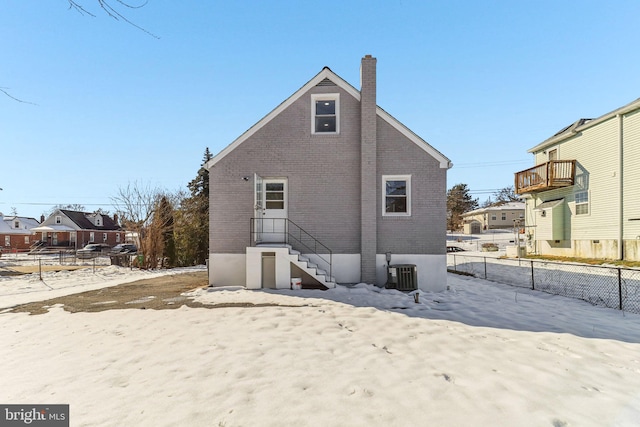 snow covered rear of property with central air condition unit