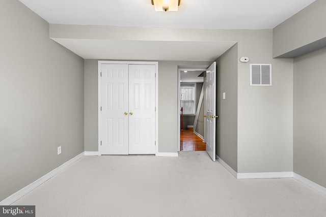 unfurnished bedroom with a closet and light colored carpet