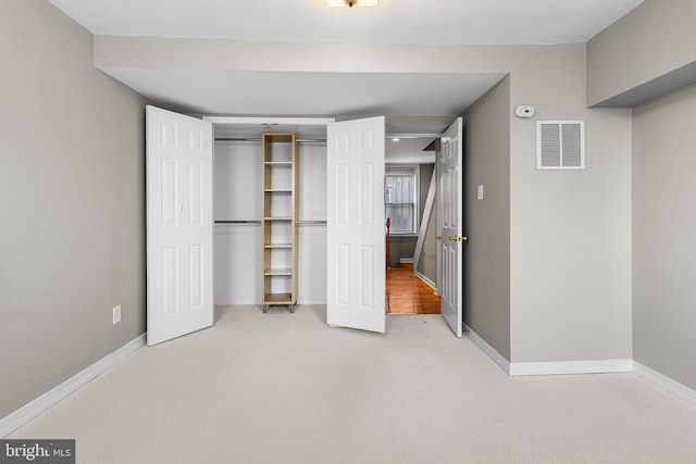 unfurnished bedroom with a closet and light colored carpet