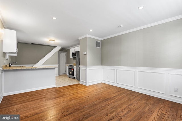 unfurnished living room with light wood finished floors, visible vents, ornamental molding, recessed lighting, and a sink