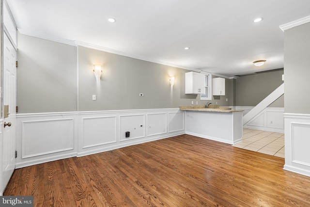 interior space featuring light hardwood / wood-style flooring, white cabinetry, kitchen peninsula, and light stone counters