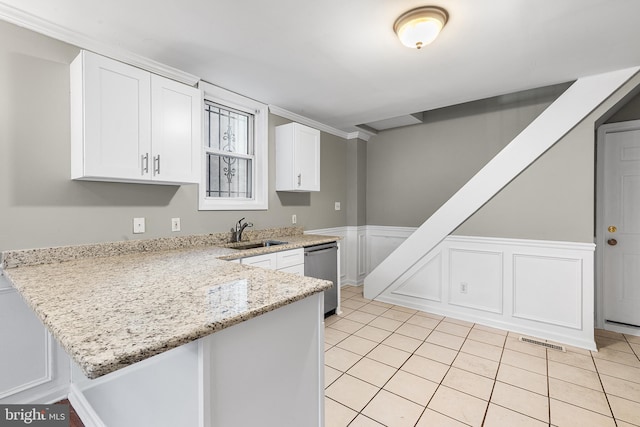 kitchen with white cabinetry, kitchen peninsula, light stone countertops, sink, and stainless steel dishwasher