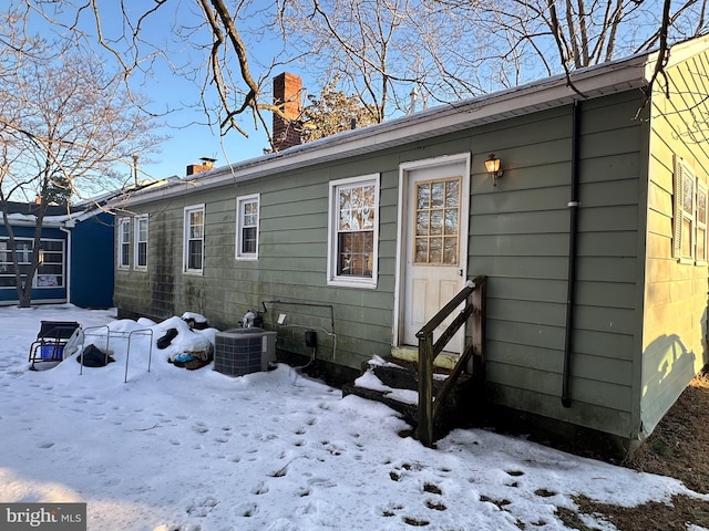 snow covered rear of property with central AC unit