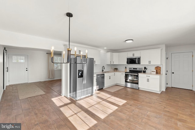 kitchen featuring stainless steel appliances, white cabinetry, sink, and pendant lighting