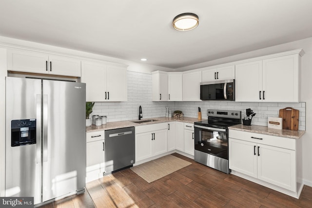 kitchen featuring appliances with stainless steel finishes, white cabinetry, light stone countertops, and sink