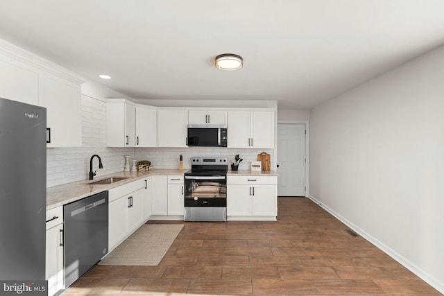 kitchen with light stone counters, white cabinets, appliances with stainless steel finishes, and sink