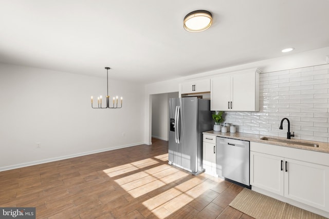 kitchen featuring a chandelier, decorative light fixtures, stainless steel appliances, white cabinetry, and sink