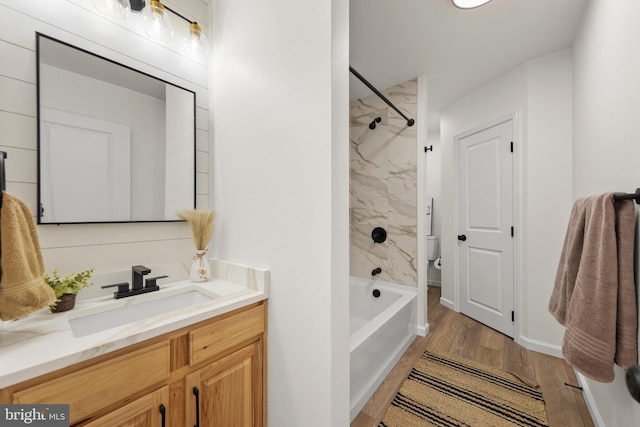 full bathroom with toilet, tiled shower / bath, vanity, and hardwood / wood-style floors