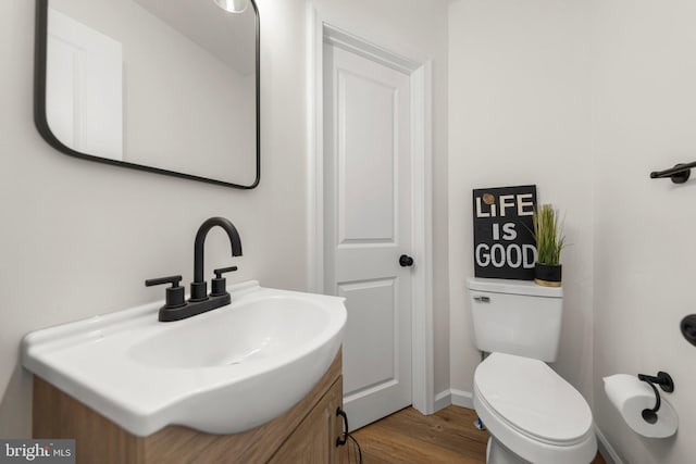 bathroom featuring toilet, wood-type flooring, and vanity