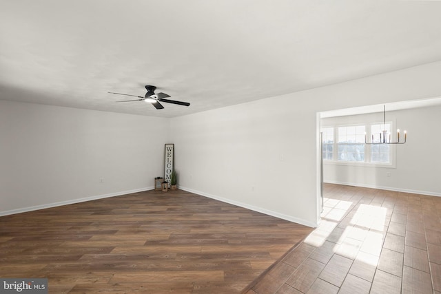 spare room with dark wood-type flooring and ceiling fan with notable chandelier