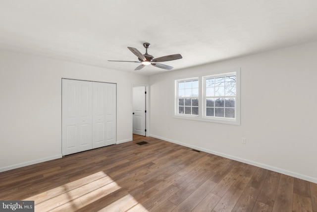 unfurnished bedroom featuring a closet, ceiling fan, and dark hardwood / wood-style flooring