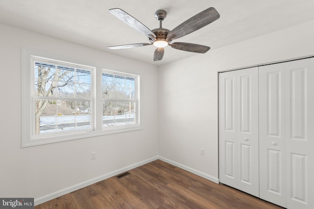 unfurnished bedroom with dark hardwood / wood-style flooring, a closet, and ceiling fan