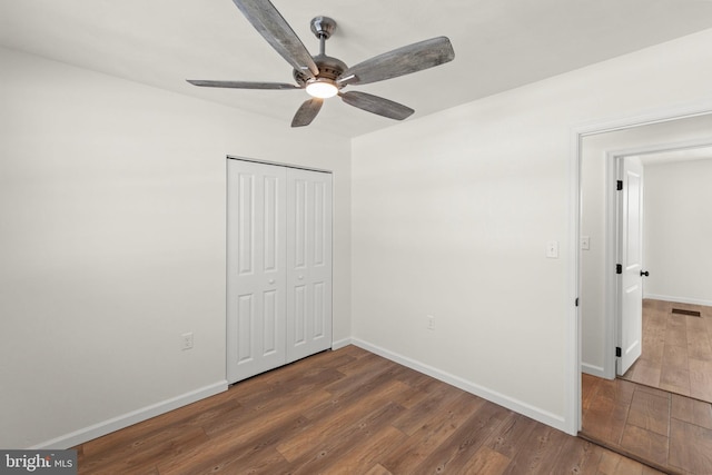 unfurnished bedroom featuring dark hardwood / wood-style flooring, a closet, and ceiling fan