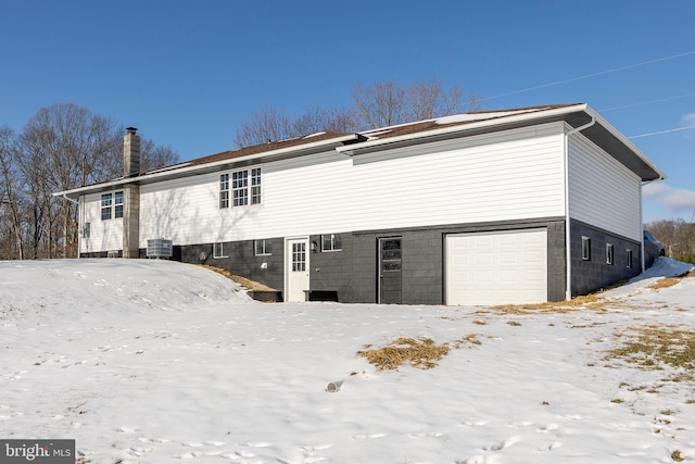 snow covered rear of property with a garage