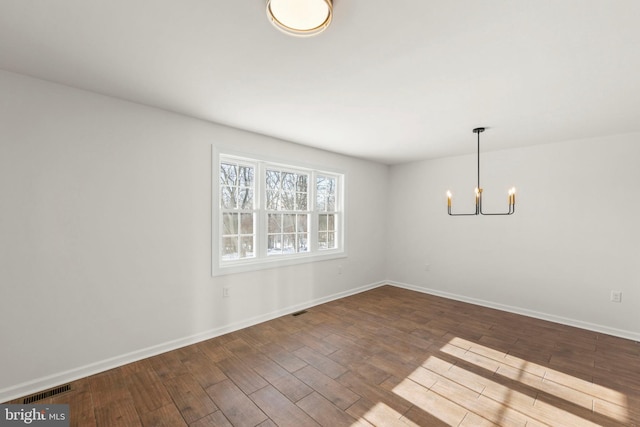 empty room with hardwood / wood-style flooring and a notable chandelier