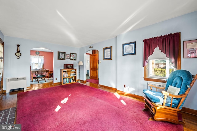 sitting room with radiator and dark wood-type flooring