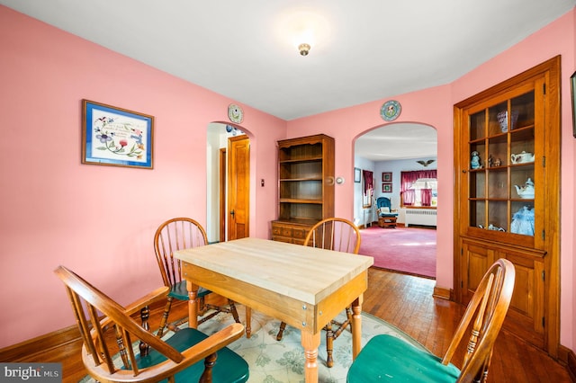 dining area featuring ceiling fan, radiator heating unit, and hardwood / wood-style flooring