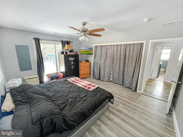 bedroom featuring ceiling fan, electric panel, and light hardwood / wood-style flooring