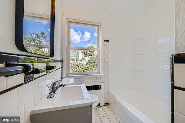 bathroom featuring radiator heating unit, vanity, toilet, and a bathing tub