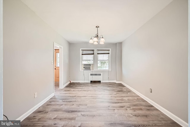 unfurnished dining area with radiator, light hardwood / wood-style flooring, cooling unit, and a notable chandelier